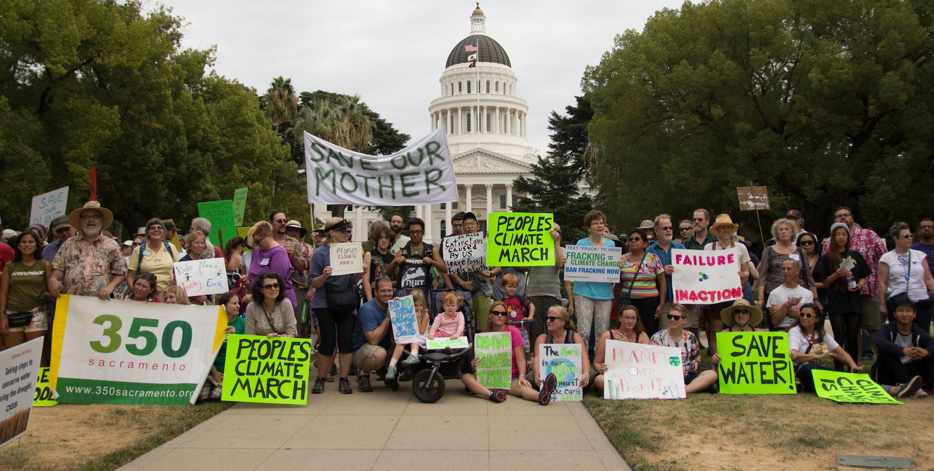 large group of people holding signs in front of the CA state capitol