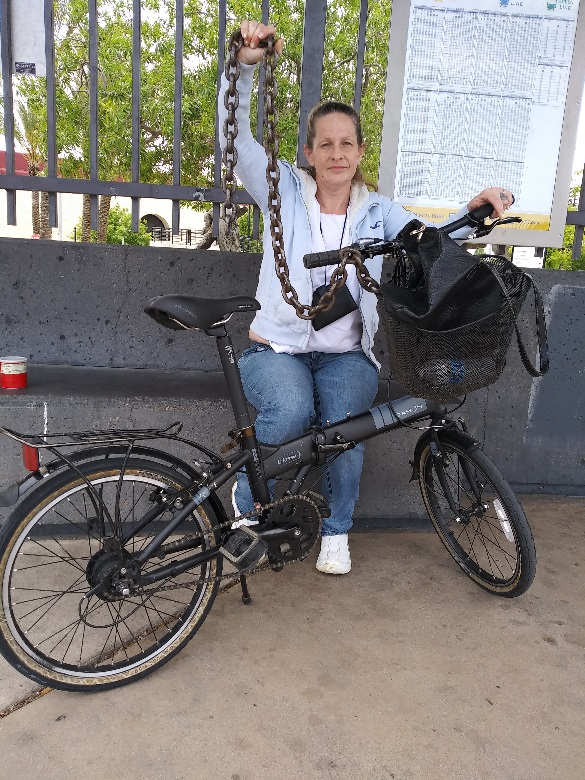a volunteer witting with her bicycle holding a large chain
