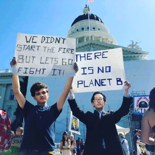Two young people standing with signs in front of the Capitol building