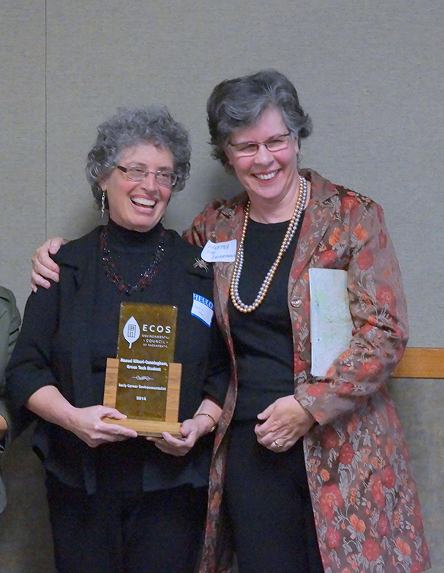 two women smiling and holding an ECOS award