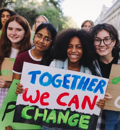 Young girls holding a sign that says, "Together we can change"